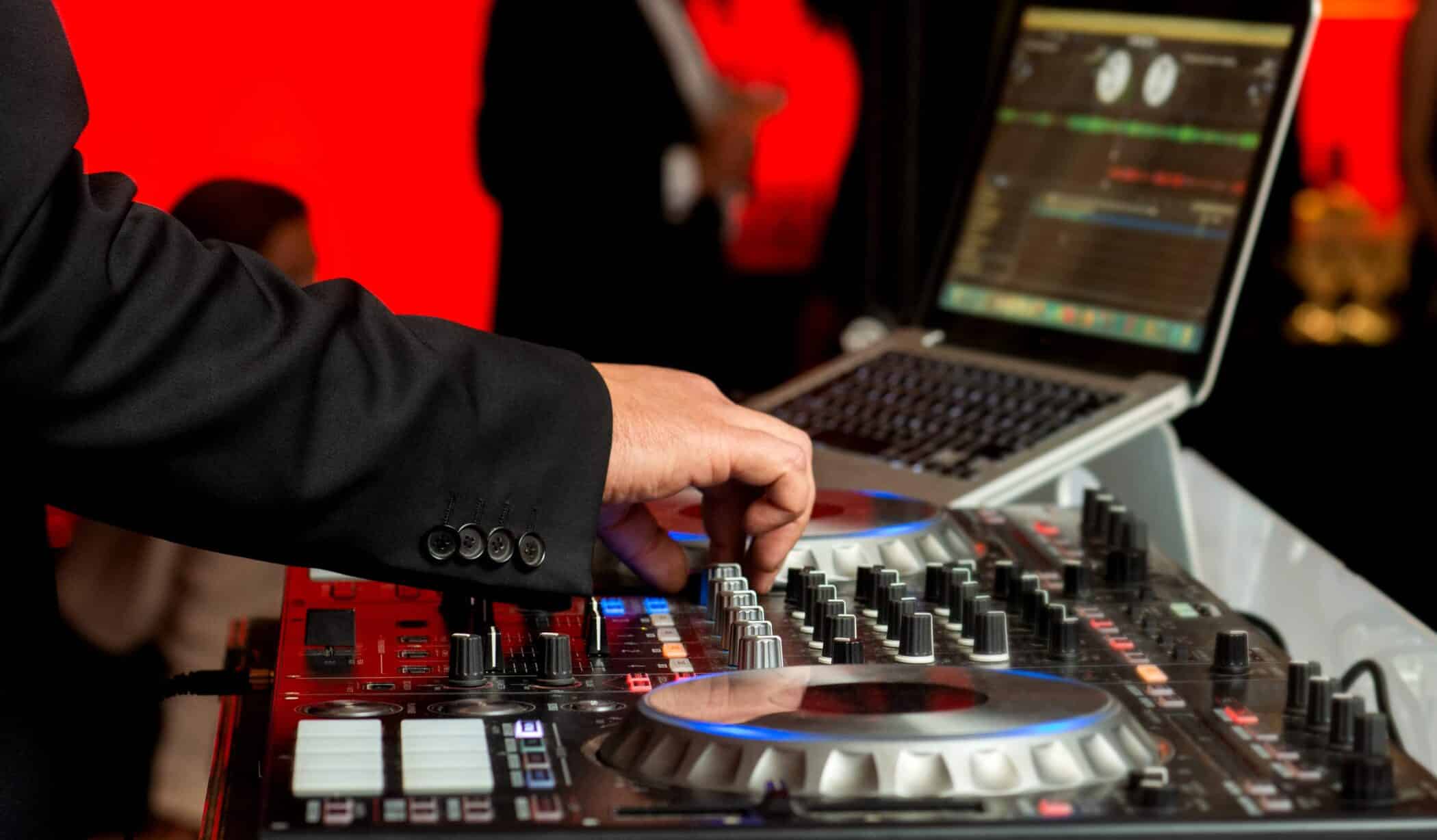 A side view of a DJ controlling his audio equipment.
